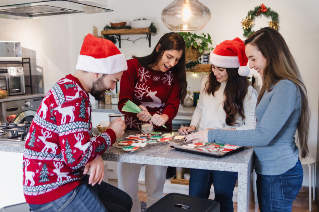 Friends laughing while decorating cookies for the holidays