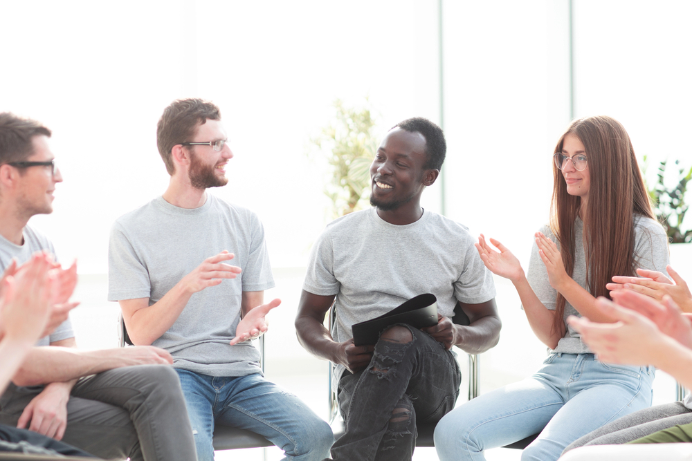 New patients for substance abuse treatment listen attentively in a group therapy session.