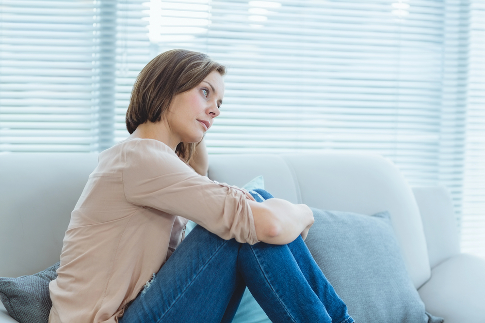 A woman sitting on a sofa, thinking.